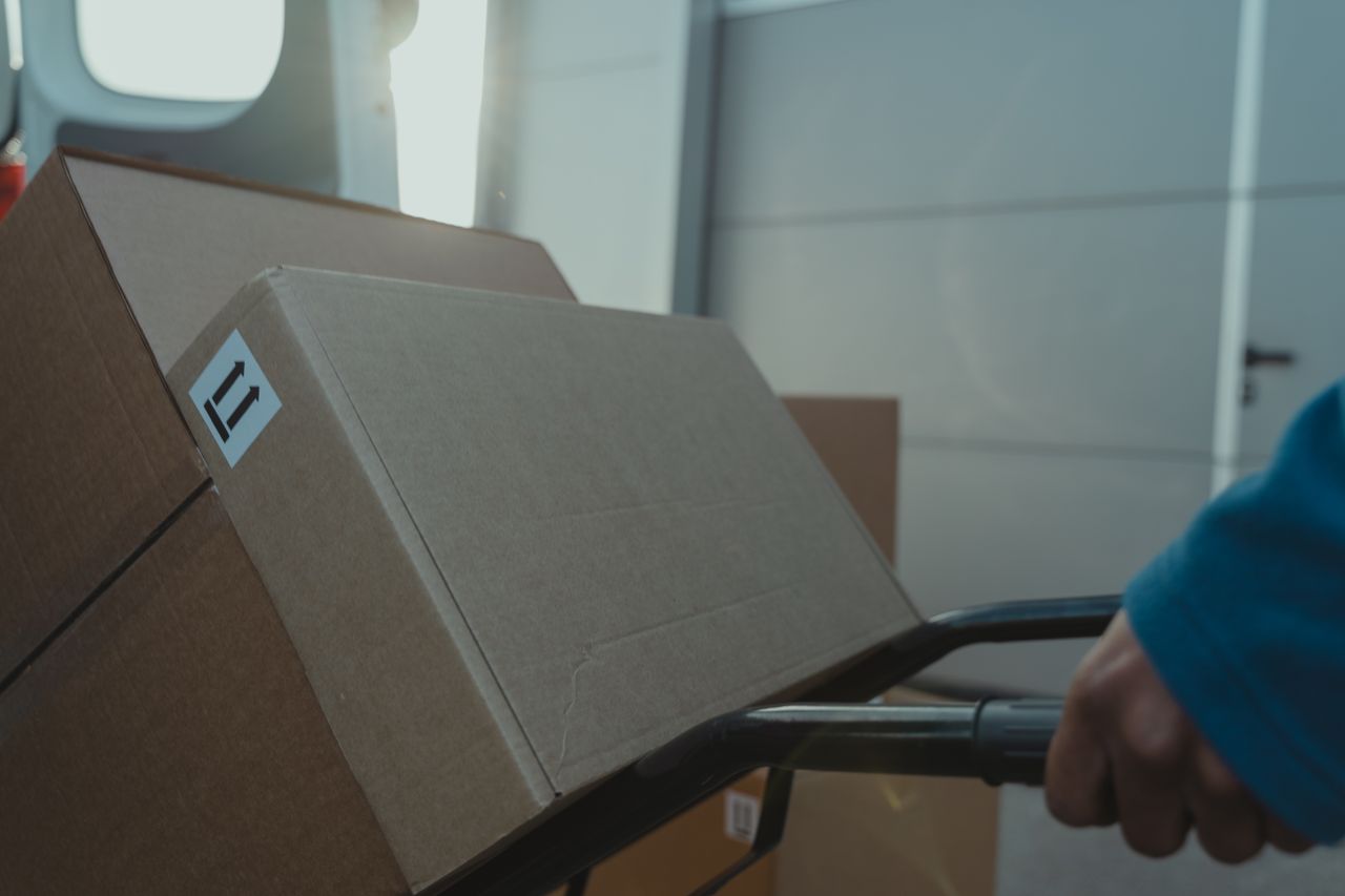 A cardboard box on a trolley inside a delivery van, showcasing logistics and shipment.